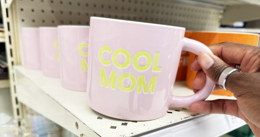 hand holding a pink mug that says "Cool Mom"