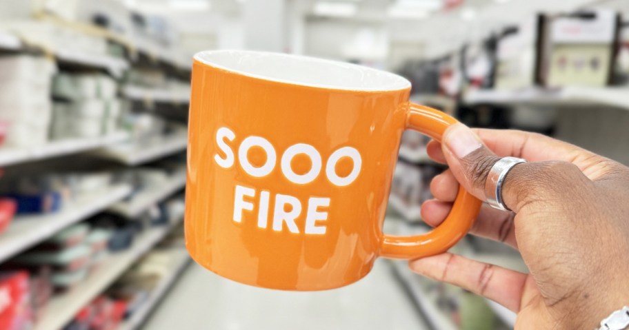 hand holding an orange mug that says "Sooo Fire"