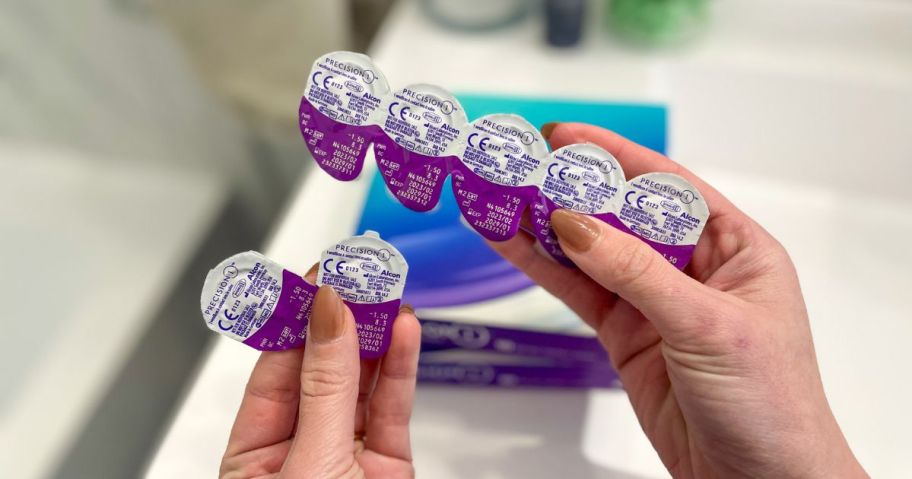 hand holding packs of contactlenses with boxes in the background