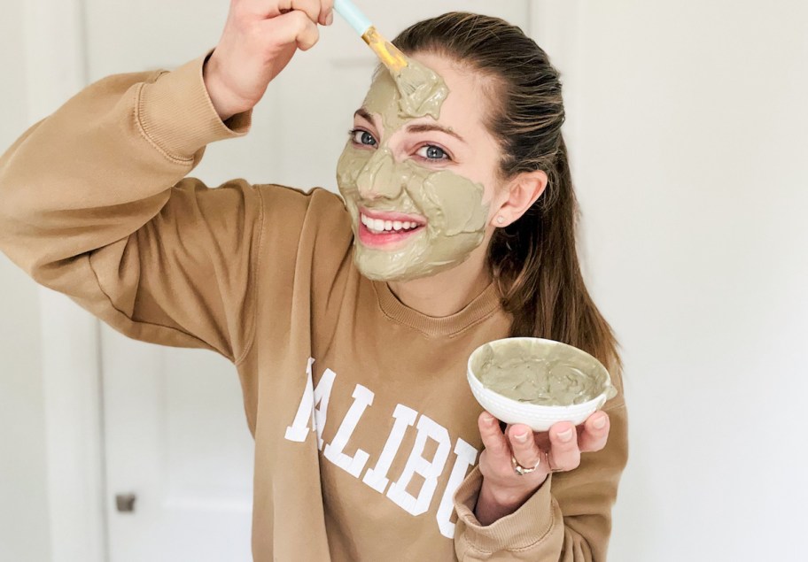 Woman applying Aztec healing clay on face