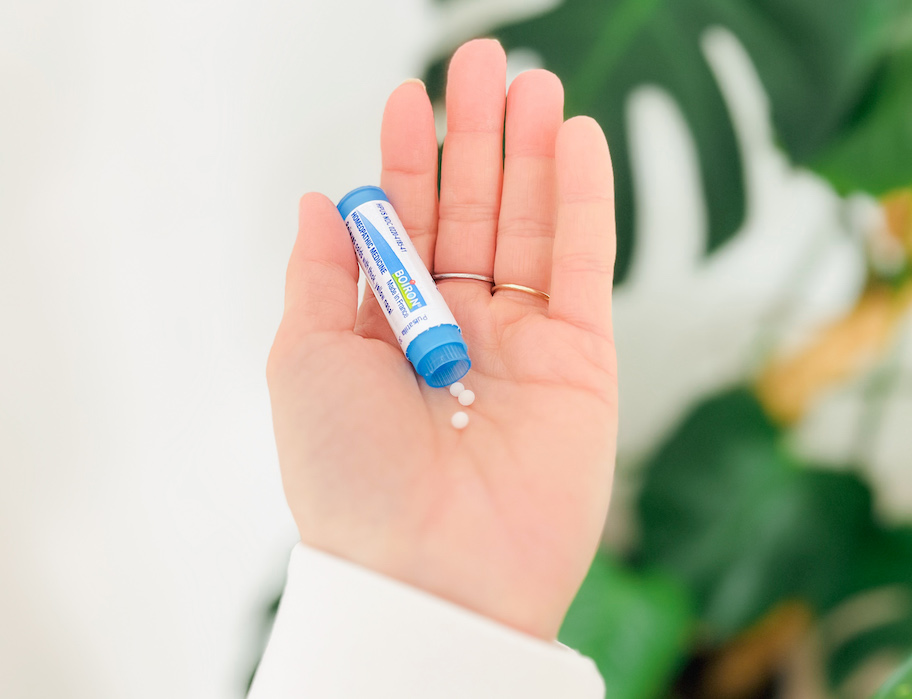 hand holding an open bottle of boiron tablets 