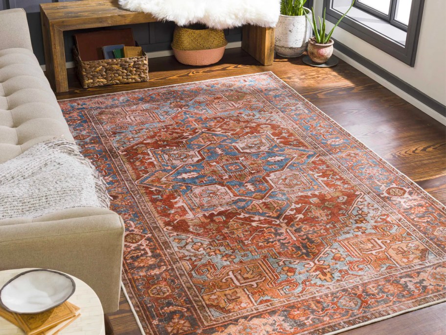 rust orange colored area rug with designs in living room next to leather couch