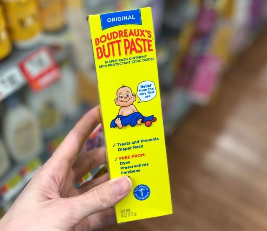 a womans hand holding a tube of boudreaux's butt paste