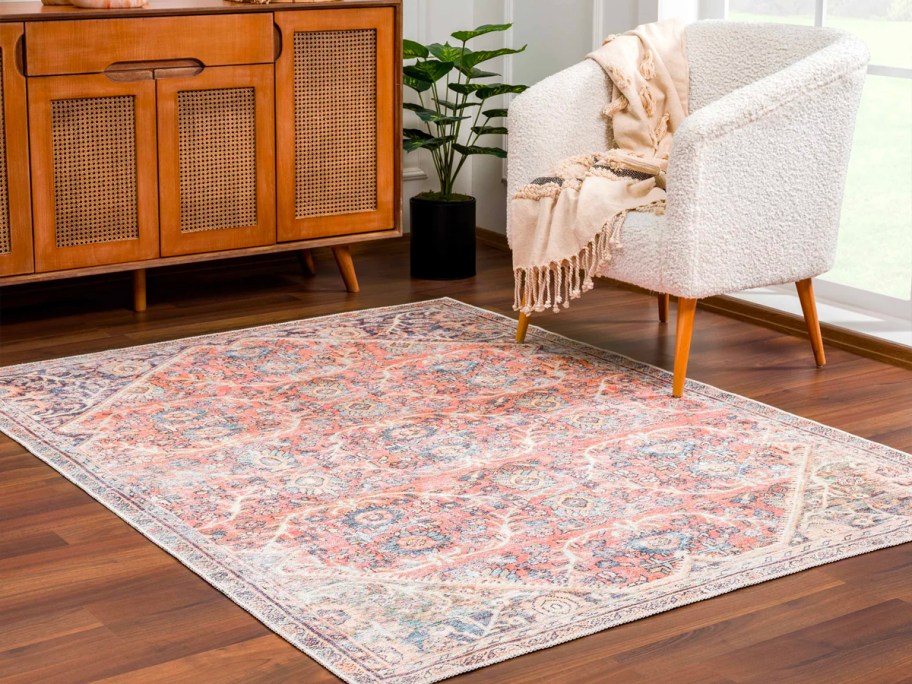 pink area rug with design on hardwood floor next to cream colored chair