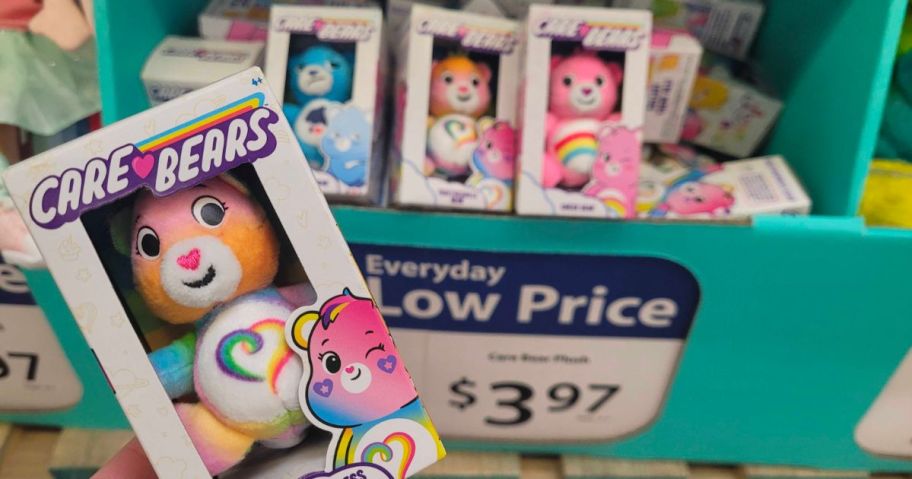 hand holding a Care Bears Micro Plush up to the camera with a bin of more in the background