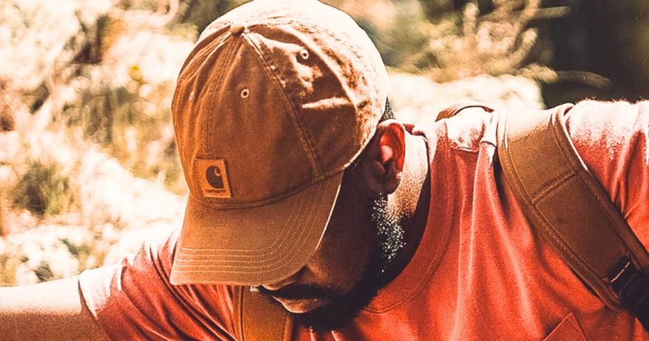 man wearing a brownish orange Carhartt hat and an orange shirt while working outdoors