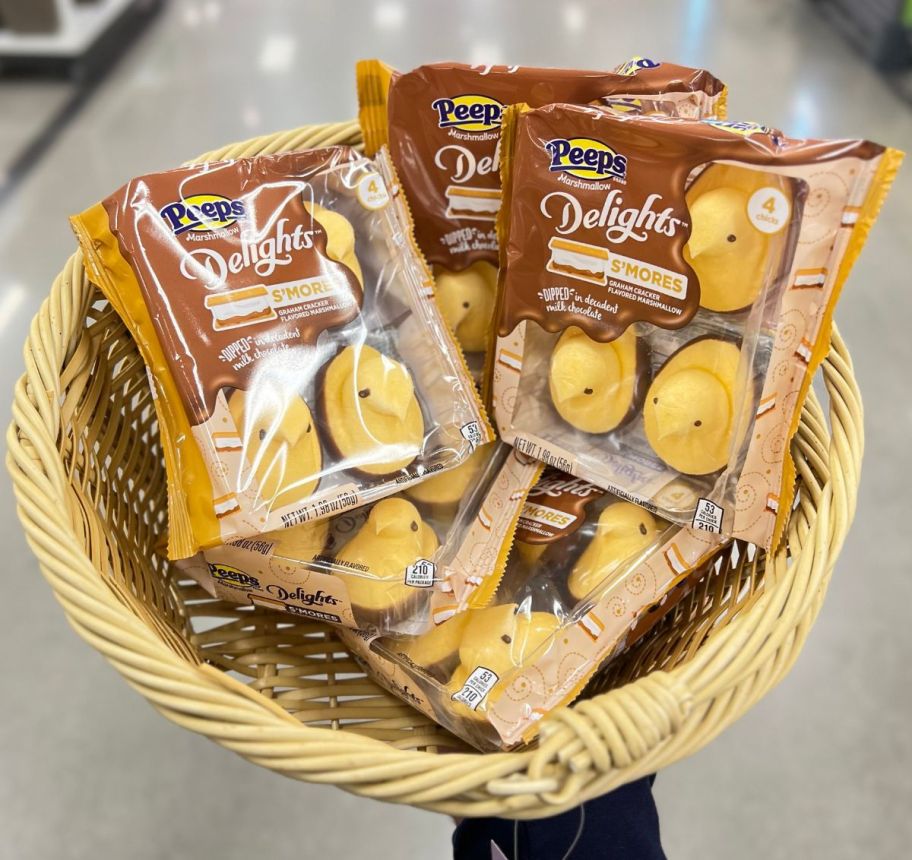 a womans hand displaying an natural colored basket containing 4 packages of smores peeps