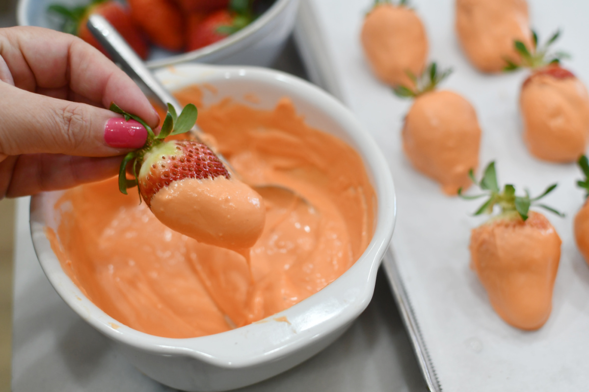 dipping strawberries into orange candy melts
