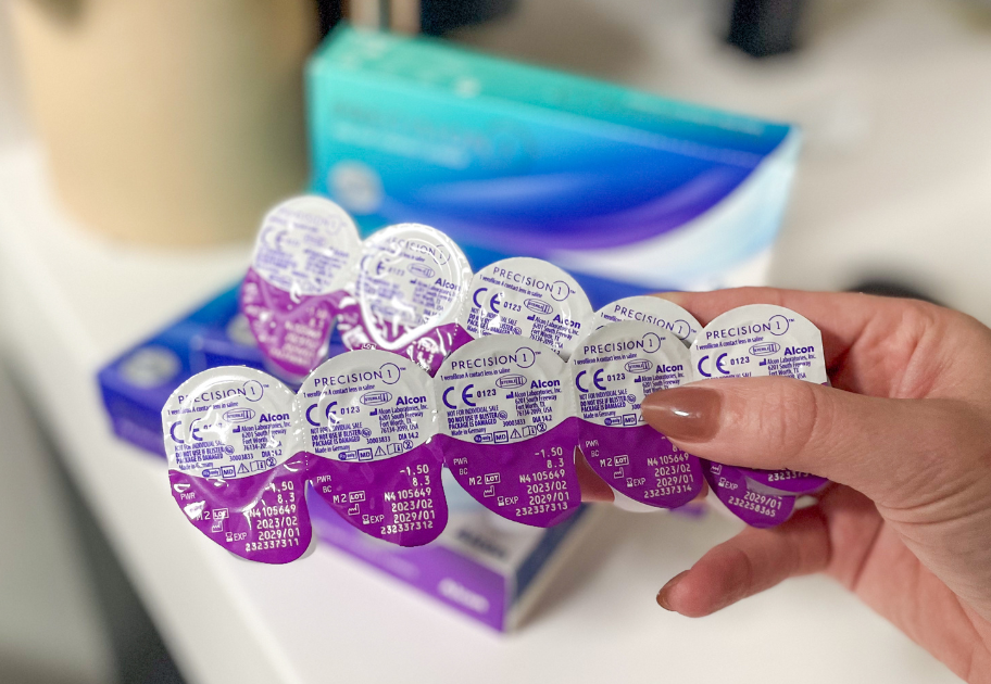 hand holding contact lenses with boxes in the background