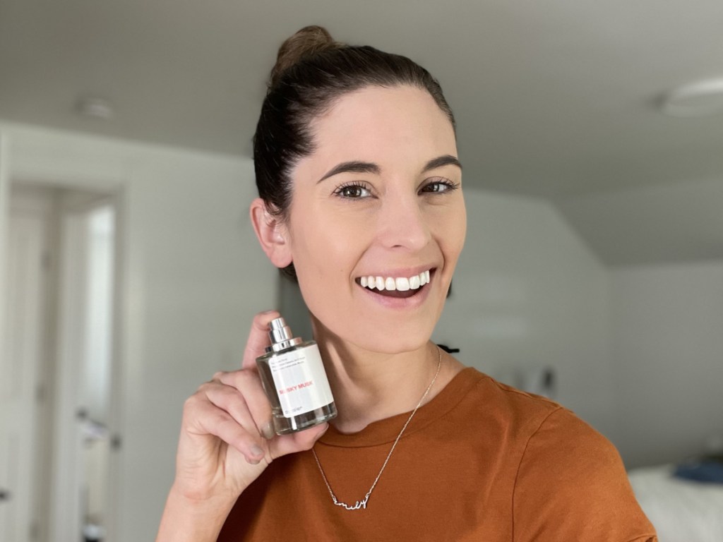 woman spraying perfume on neck