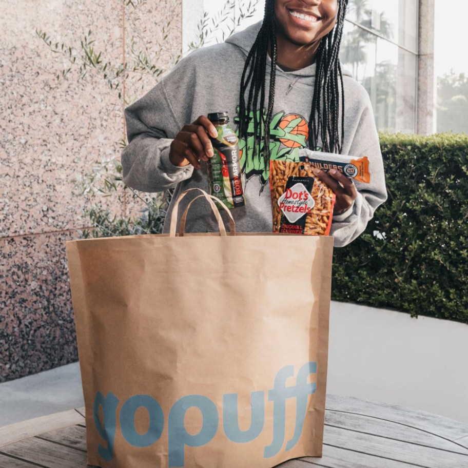 person standing behind bag full of groceries