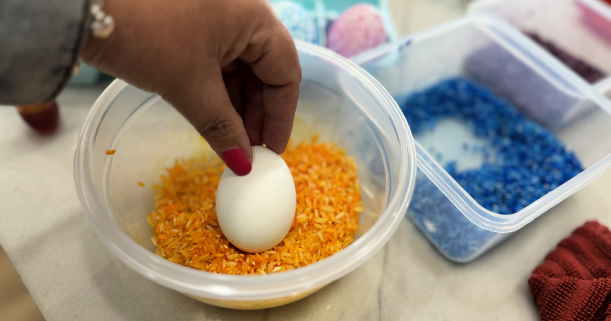 placing a hard-boiled egg into a container with dyed rice