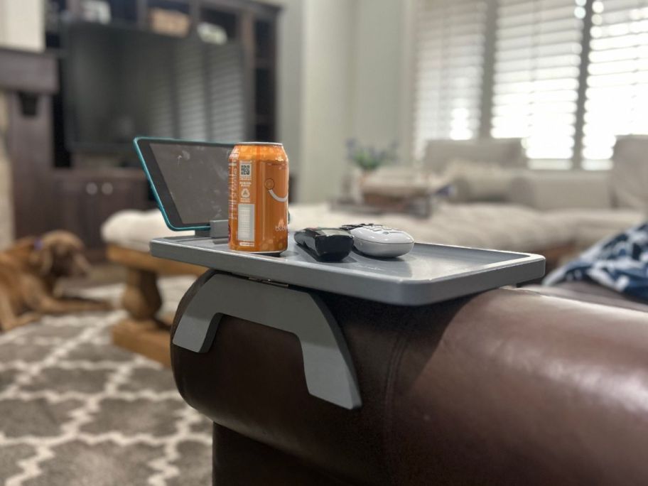 grey sofa arm tray on a brown sofa with remotes, canned drink and tablet on it