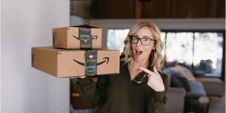 Collin holding Amazon boxes and pointing to them with her other hand