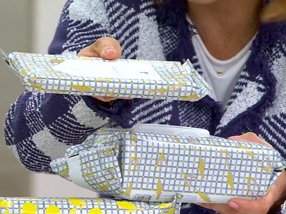 Woman comparing a regular 30-count pack of Beekman wipes to te supersize 100-count pack of the same wipes