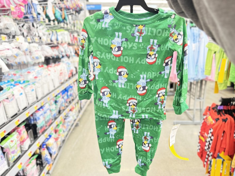 hand holding up set of christmas bluey print pajamas on hanger