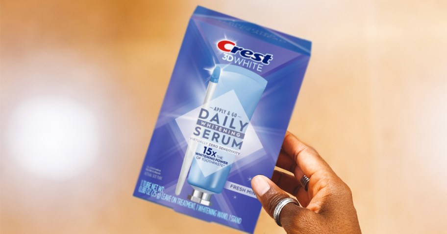 hand holding purple box of Crest 3D White Daily Whitening Serum