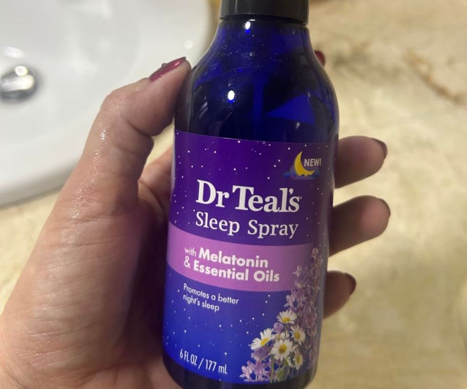 A hand holding Dr Teal's Sleep Spray