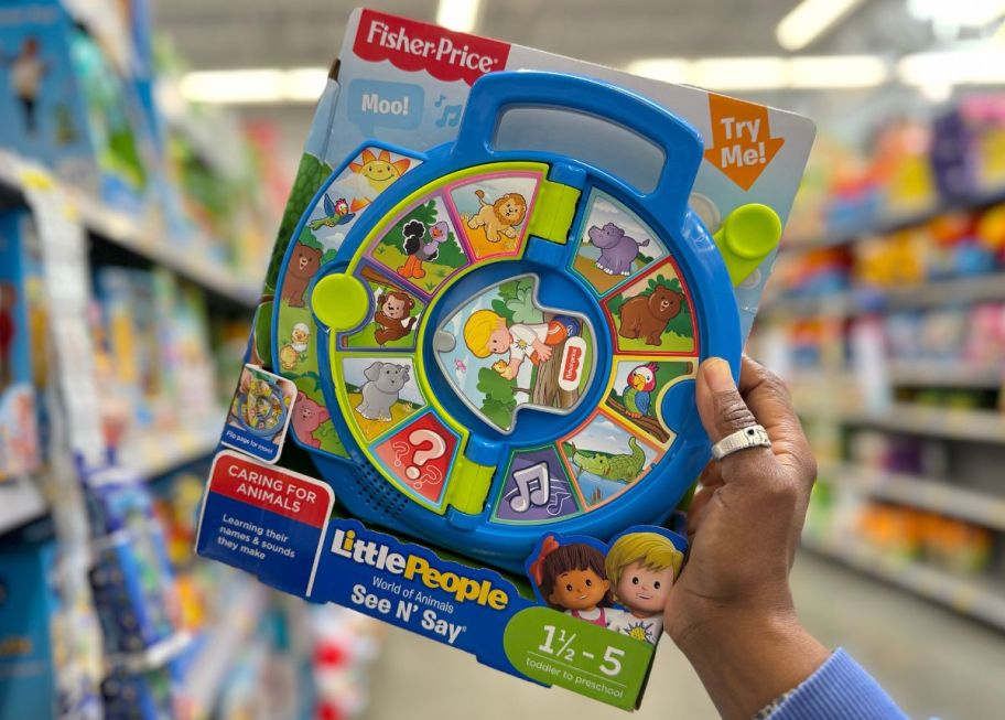 a womans hand holding a Fisher Price Little People World of Animals See N Say
