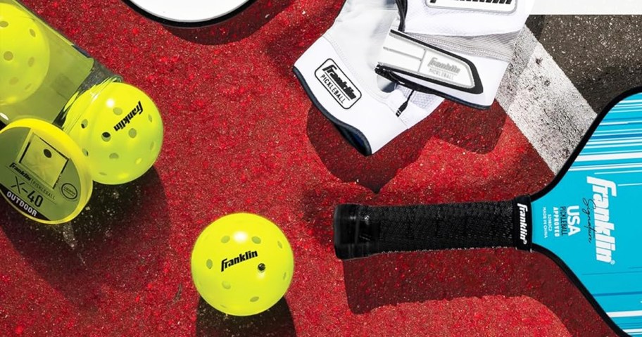 pickleball paddle, balls, and gloves on ground in court