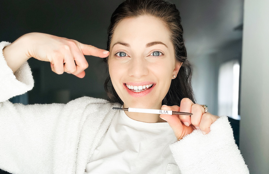 woman holding up finger pointing to eyebrow pencil