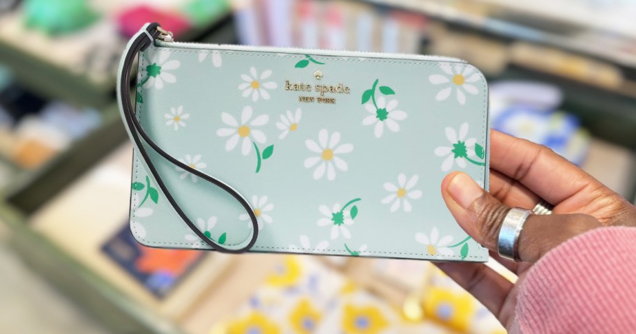 hand holding up a daisy print kate spade wristlet