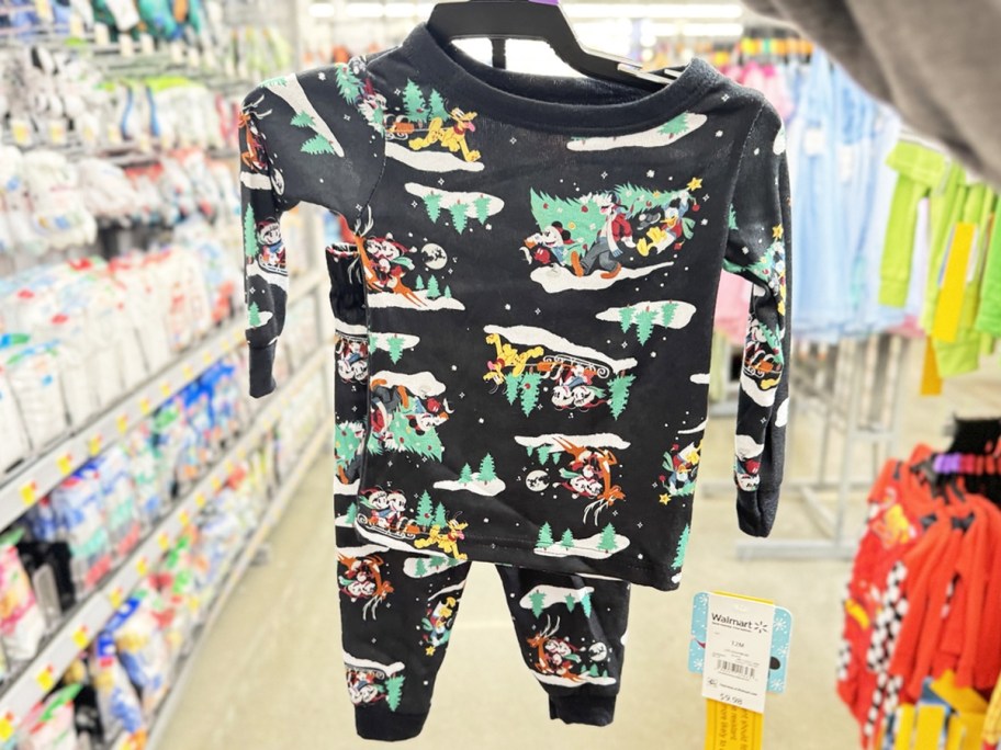 hand holding up set of christmas mickey mouse print pajamas on hanger