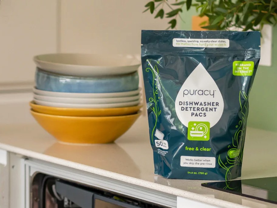 bag of Puracy Dishwasher Pods on kitchen counter near stack of bowls