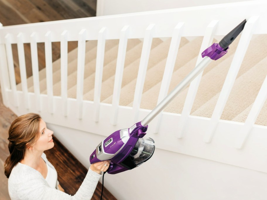 woman using a Shark Rocket Pet Pro Corded Stick Vacuum to clean stair railings