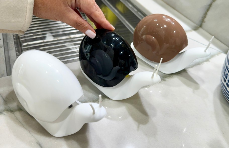 Three snail shaped soap dispensers on a kitchen counter