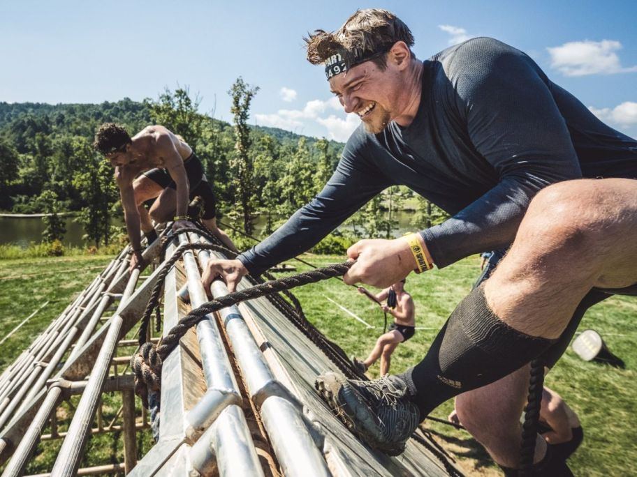 A man climbing over a wall during a Spartan race