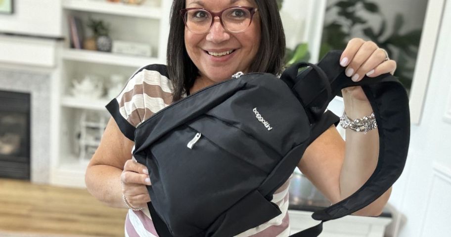 Woman holding a black Baggallini sling bag