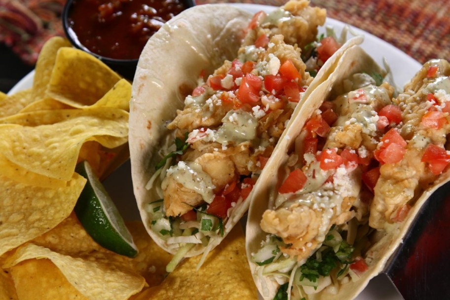 two tacos on a plate with tortilla chips