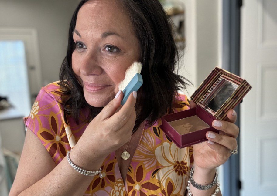 woman applying bronzer to cheek