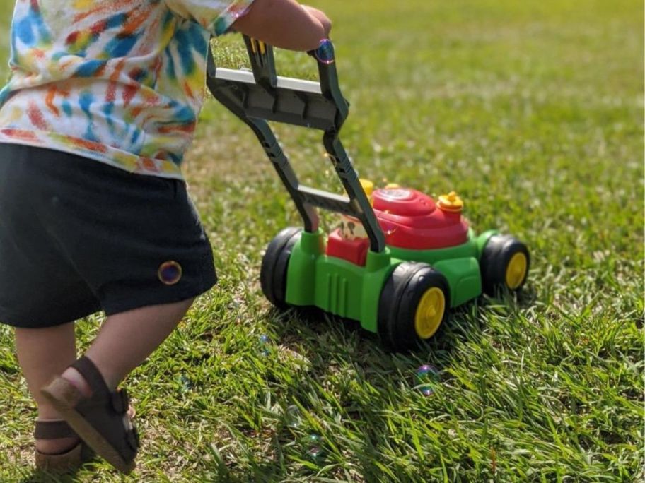kid pushing bubble lawn mower on grass