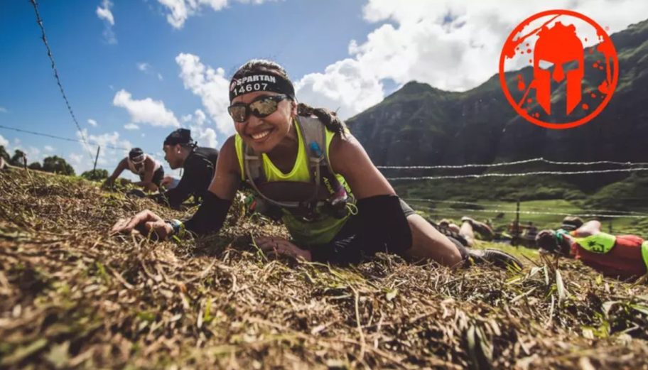 woman crawling on ground for spartan race