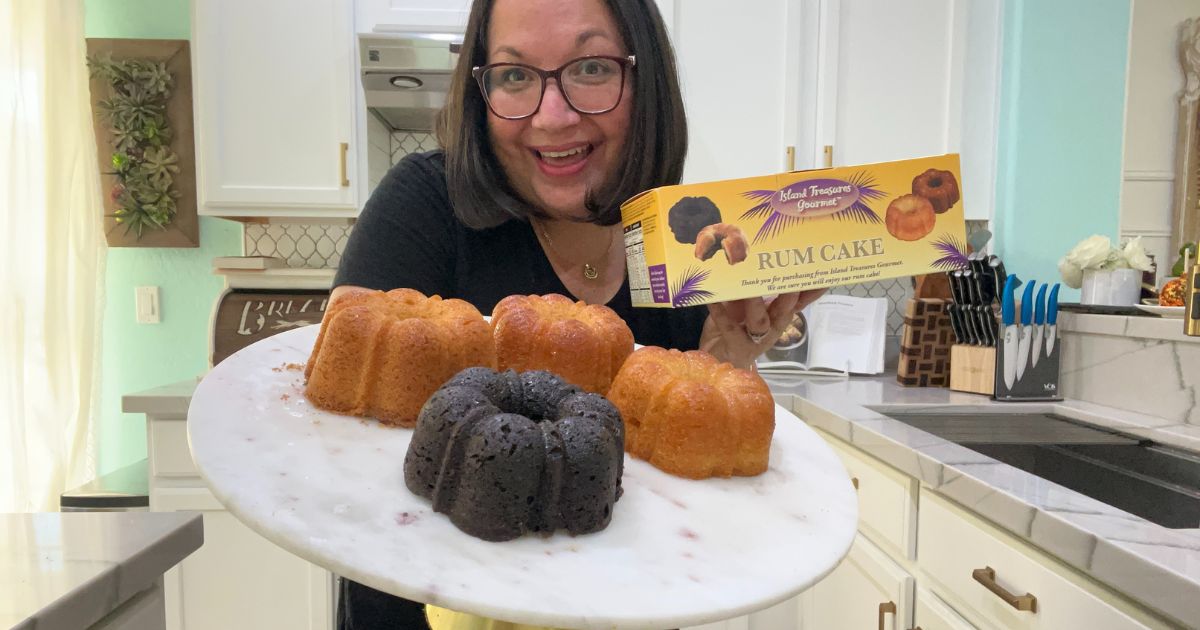 a woman holding a cake plate with 4 small rum cakes on it it one hand and a rum cake box in the other