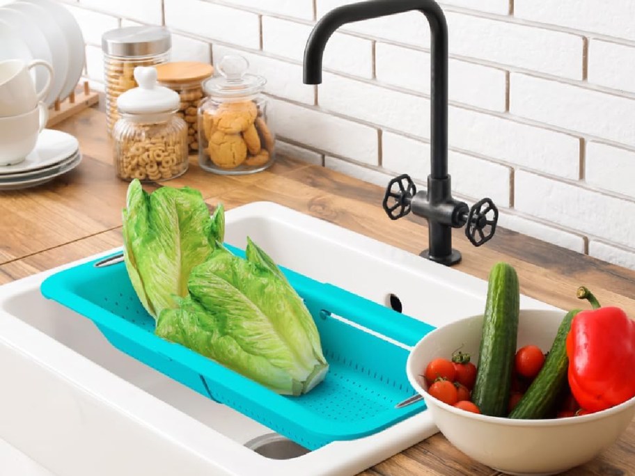 kitchen with colander on the sink with veggies next to it