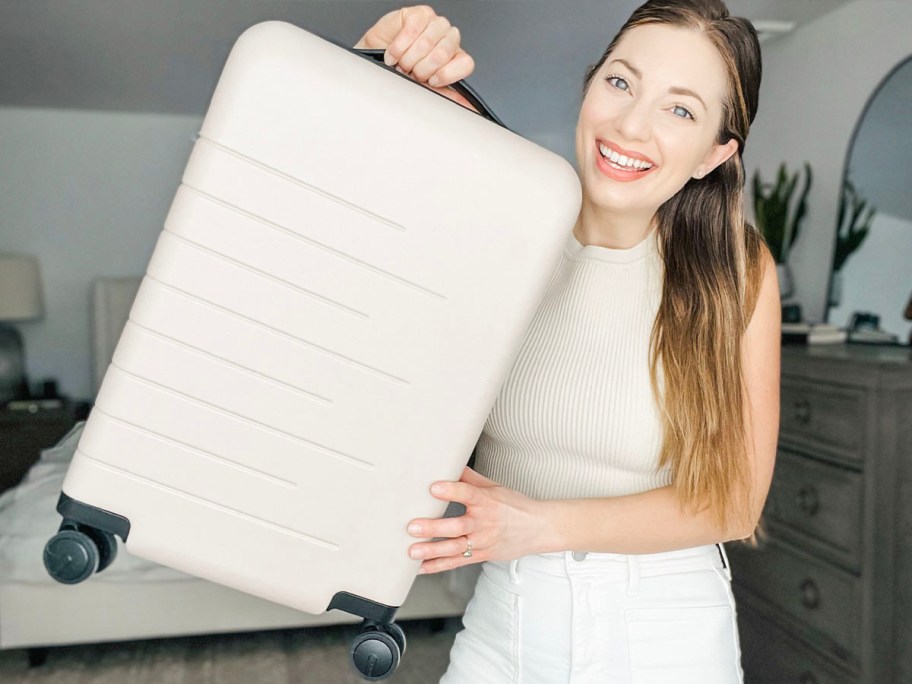 woman holding tan luggage