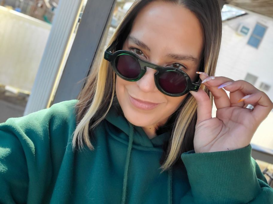 woman wearing green sweatshirt and round green sunglasses