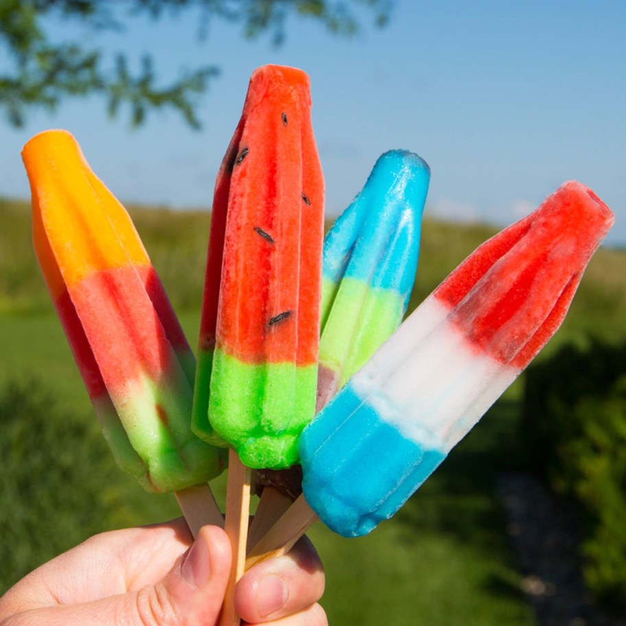 hand holding up various Bomb Pops flavors