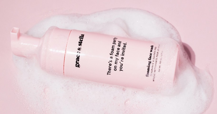 pink bottle of Grace & Stella Foaming Facial Cleanser surrounded by foam