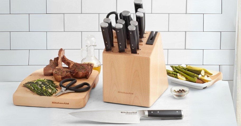 KitchenAid knife block set on counter next to cutting board with meat on it and a bowl of veggies 