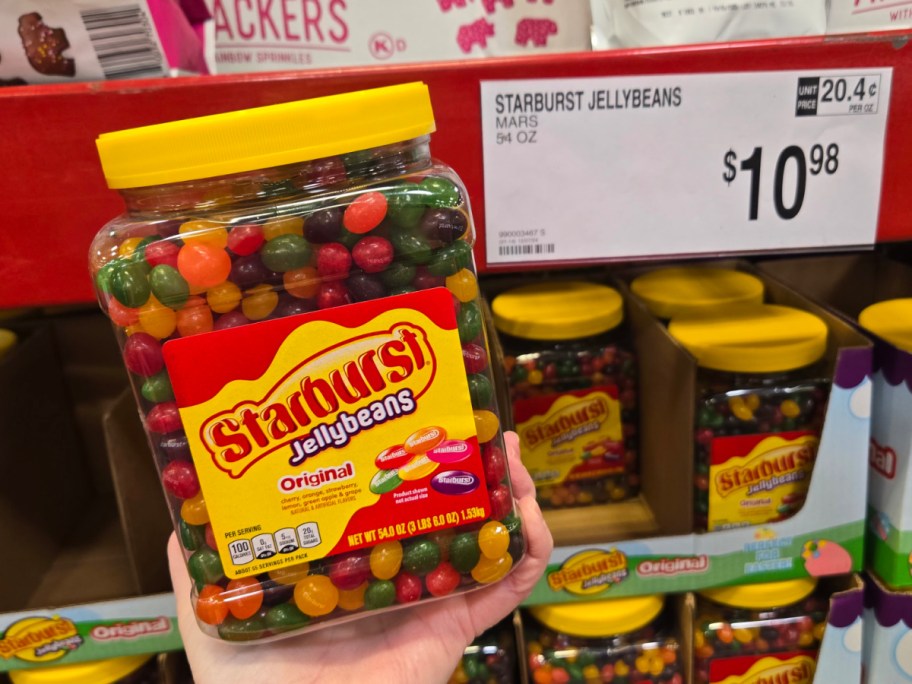 Hand holding Starburst Original Assorted Jelly Beans 54oz Bulk Jar