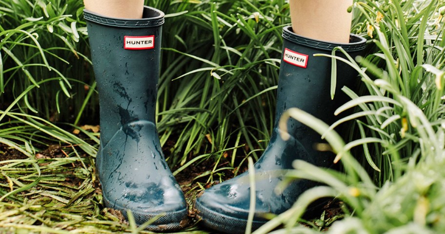 girl standing in tall grass wearing a pair of hunter rain boots