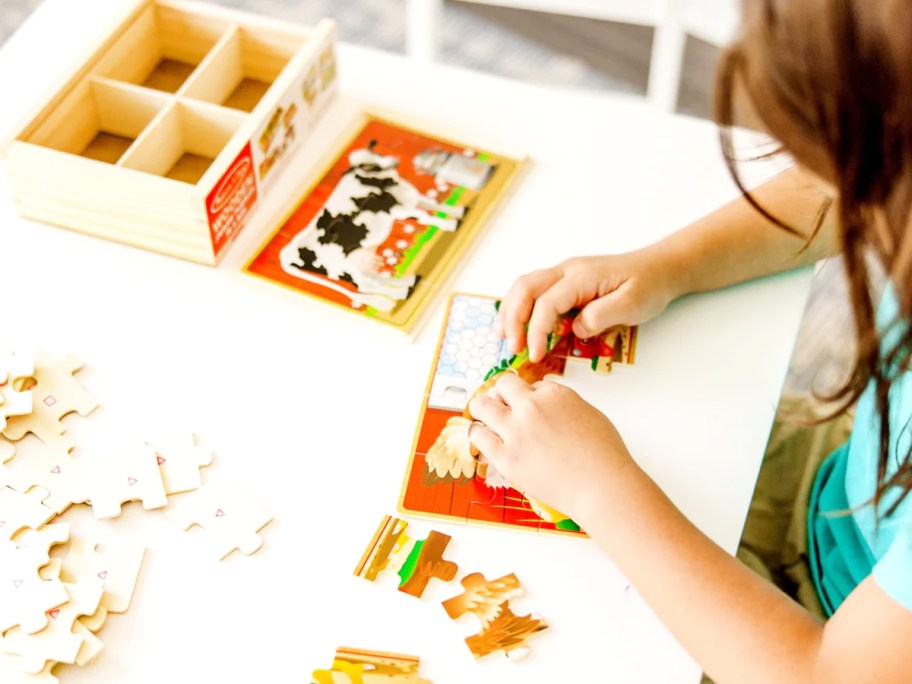 girl completing farm animal wooden mini puzzles