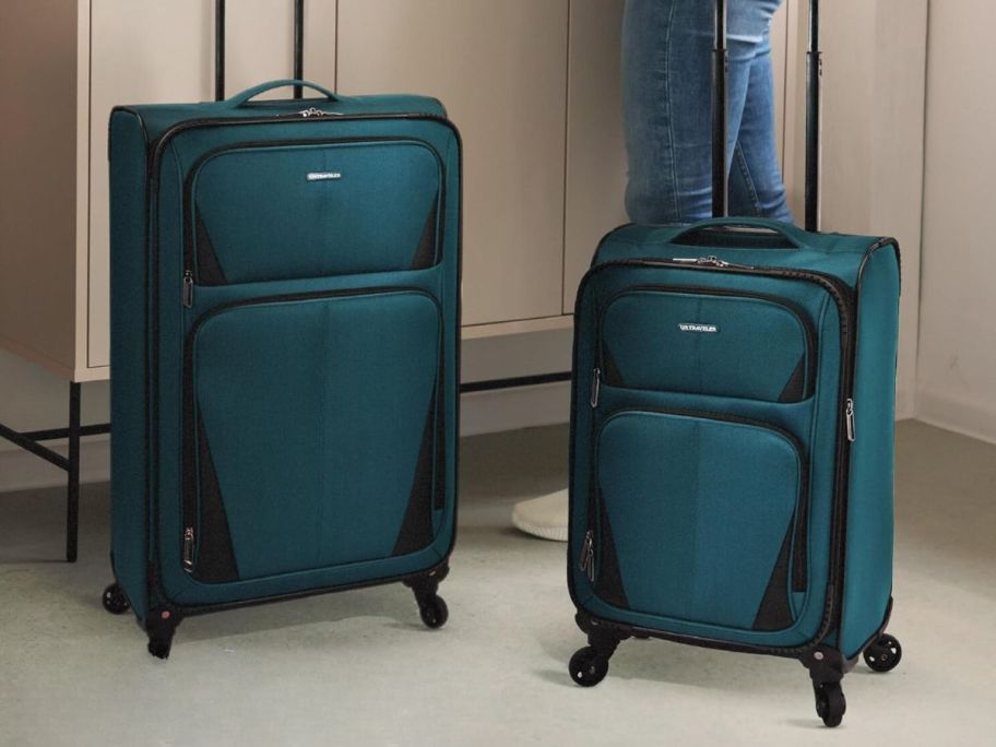 2 green luggage pieces in a kitchen