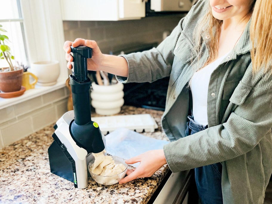 woman pushing down chute on Yonanas frozen treat maker with soft serving coming out into a bowl