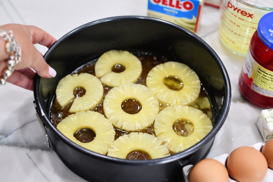 adding pineapple slices to cake pan