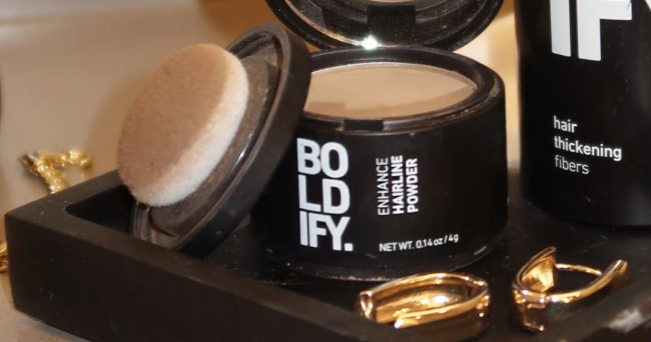 container of hairline powder on a vanity with gold earrings